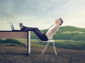 businessman-relaxing-at-his-desk-in-the-middle-of-a-green-meadow